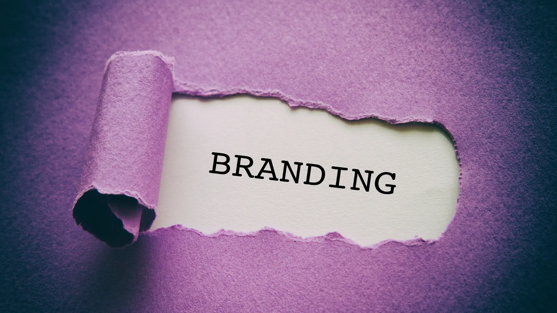 A torn purple paper revealing the word 'BRANDING' on a white background, symbolizing the concept of brand identity and marketing.