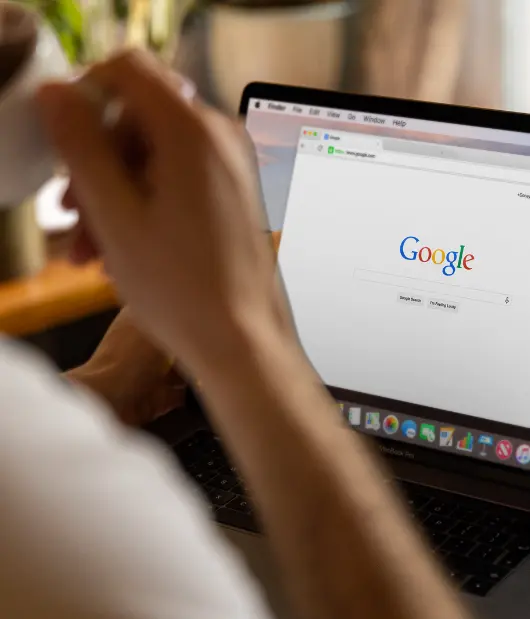 Person using a laptop with Google search open on the screen – Digital marketing services by Uzmate