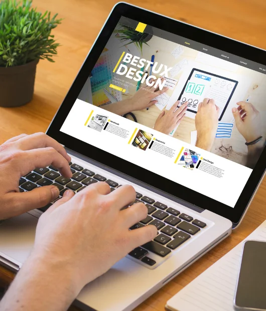 A laptop screen showing a UX design website with a clean and modern interface, featuring hands working on a project.