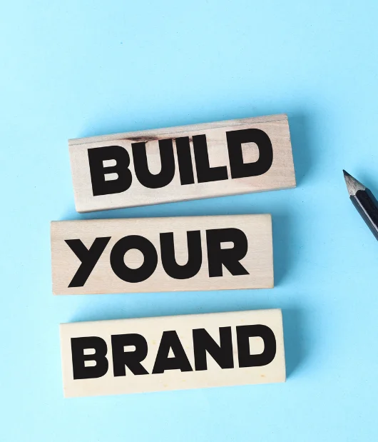 Wooden blocks with bold black text spelling 'BUILD YOUR BRAND' on a blue background, symbolizing brand development.