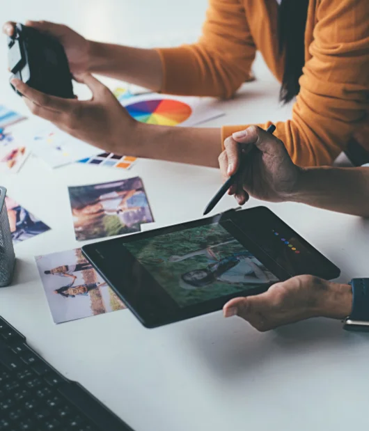 A designer creating a branding mood board with colorful images, design elements, and brand inspiration spread across a wooden table.